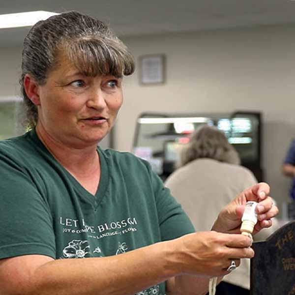 Vendor at Quapaw Farmers Market showing a handmade item to a customer inside the food hub.