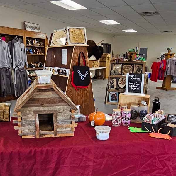 Quapaw Farmers Market table with handmade crafts, wood display, candles, and seasonal items inside the food hub.